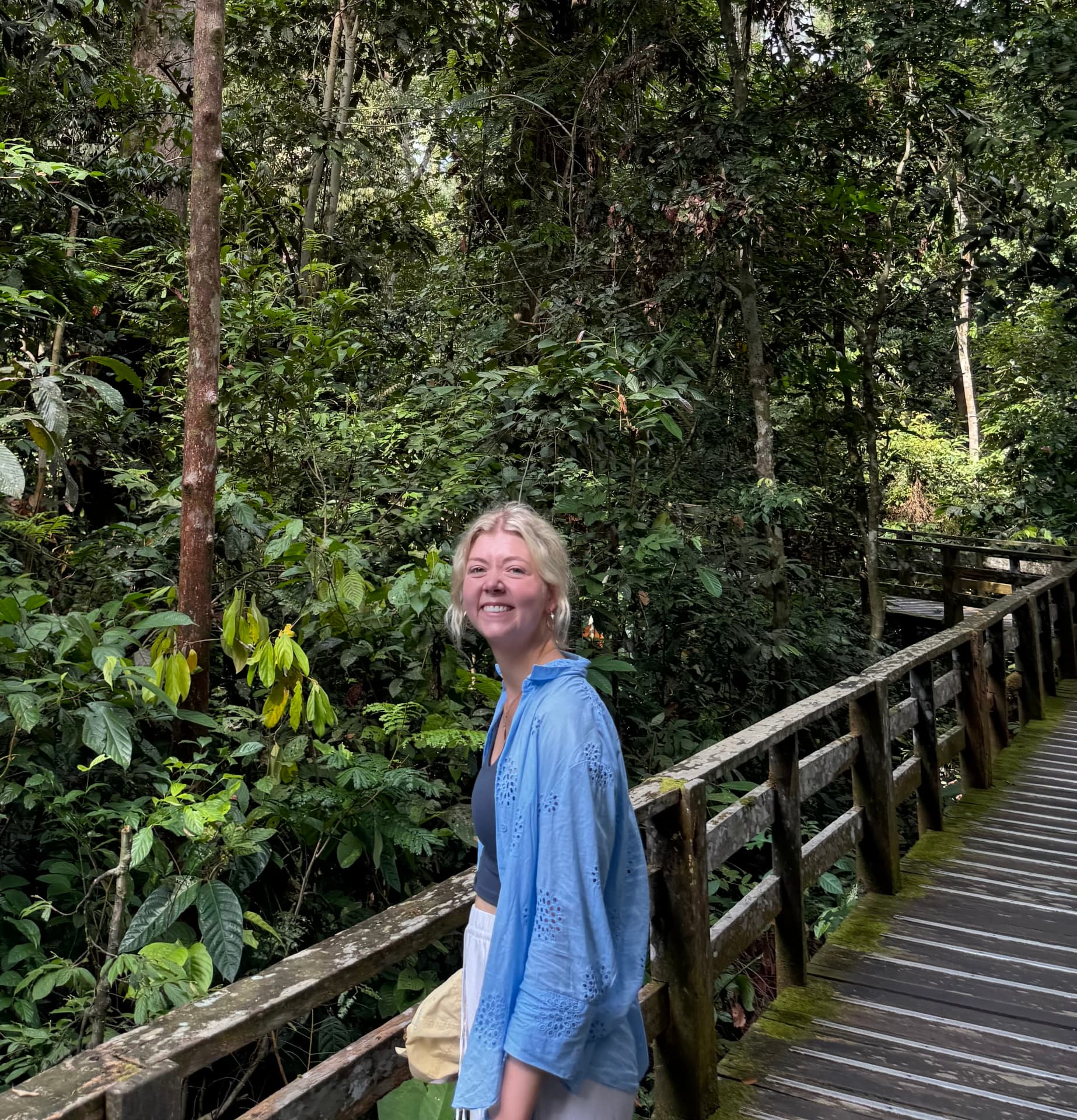 Louise, founder of Living Learning, smiling on a rainforest boardwalk surrounded by greenery